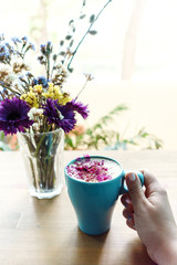 Bouquet of flowers and attractive girl hand holding cup of aroma cappuccino