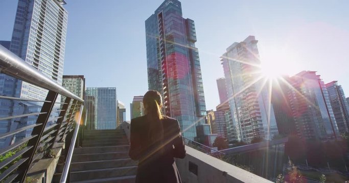 Business woman walking on stairs outside using smartphone drinking coffee in Vancouver, Canada. Female urban young professional businesswoman. RED EPIC SLOW MOTION.