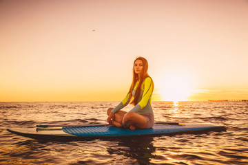 Fototapeta na wymiar Stand up paddle boarding on a quiet sea with warm summer sunset colors