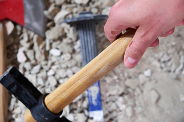 A hand holding hammer on the background of work tools and rubble
