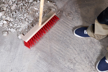 Workman sweeping the rubble on the floor with a broom