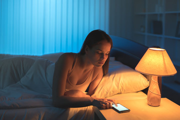 Fototapeta premium The attractive woman phone in the bed. night time
