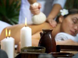 portrait of young beautiful woman in spa environment. focused on candles.