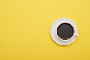 Flat lay of yellow desk with cup of aromatic coffee