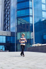 Good-looking boy looking around while walking with food and listening music