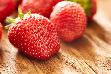 Close-up of the fresh red strawberries on the brown wooden table.
