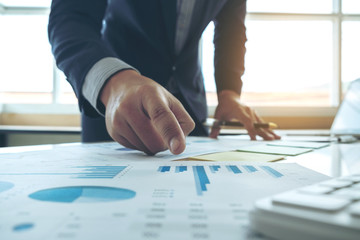 Close up of hand's business man working and pointing to graph document finance project with laptop in home office. business concept