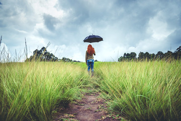 Women standing umbrella On the green meadow in the rainy season. Asian women
