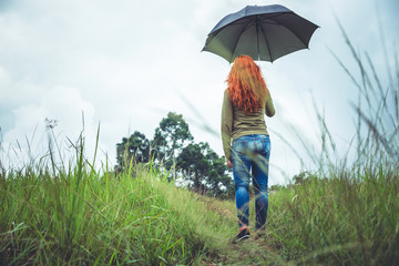 Women standing umbrella On the green meadow in the rainy season. Asian women