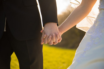 Young couple full of love at marriage hold their hands while sundown 