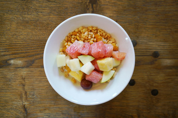 Fresh fruits and cereal in a bowl on old wood table