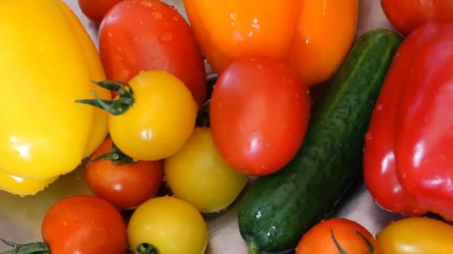 Water splashing on bell peppers in slow motion; shot on Phantom Flex Juicy fresh vegetables lie in the metal sink after washing. Green cucumber, okanzhevy pepper, yellow tomato. HD 25