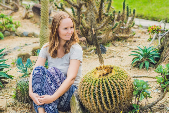 A Young Woman Sits On The Ground Among The Cactus. Spiny Concept. Out Of Comfort Zone Concept