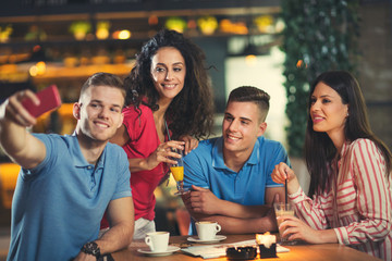 Group of young people meeting in a cafe make selfie photo.