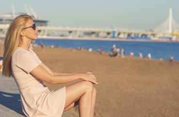 Fototapeta na wymiar Pretty young blonde woman sitting at the seashore
