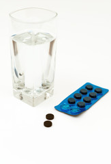 Activated carbon pills and glass of water.
