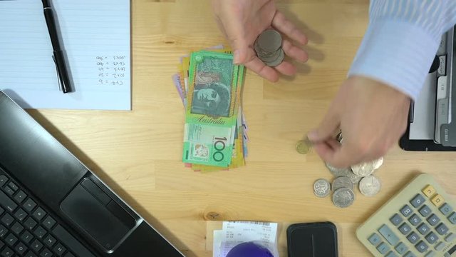 Business man counting cash at desk overhead, counting coins, real time.