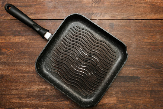 Empty square grill pan on wooden table. Black kitchenware top view