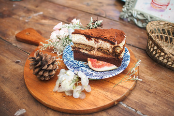 Tiramisu dessert cake sliced on a wooden serving board on wooden table.