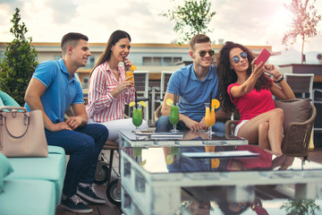 Friends having fun and drinking cocktails outdoor on a rooftop bar