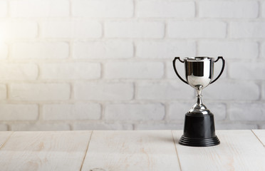trophy over wooden table against white brick wall with Text Space