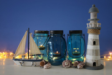Magical mason jars whith candle light and wooden boat on the shelf. Nautical concept
