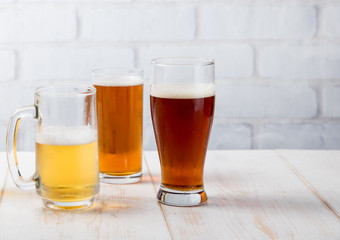 Beer glasses with various beer on wood table against white brick wall