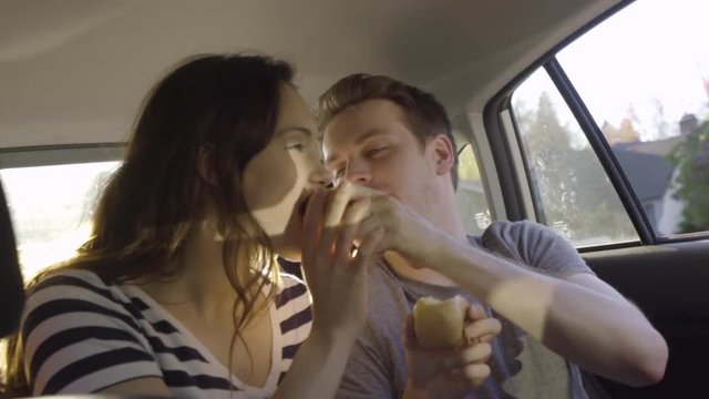 Couple Sit In Backseat Of Moving Car, Man Gives His Girlfriend A Bite Of His Apple, Slow Motion