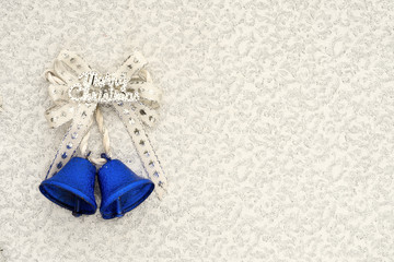 blue jingle bells with a silver ribbon bow and merry christmas writing on a silver background