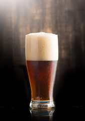 Glass of dark beer over on dark wooden background
