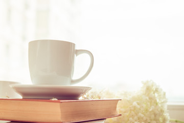 cup of tea or coffee on a brown book. Breakfast or snack. Flowers hydrangeas. Toning