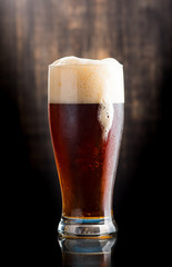 Glass of dark beer over on dark wooden background