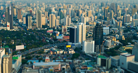 Fototapeta na wymiar City scape with modern skyscrapers and express way against with slum houses in front of. Bangkok aerial view evening panorama, tilt-shift effect.