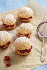 Eclairs with mascarpone cream and raspberries.