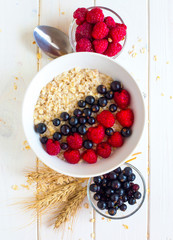 Plate of oatmeal with blueberries and raspberries on white background. Vegetarian breakfast. 