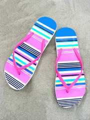 Colorful flip-flops on a beach sand 