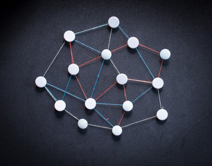 Fototapeta premium Colorful wool threads form a network between pins.