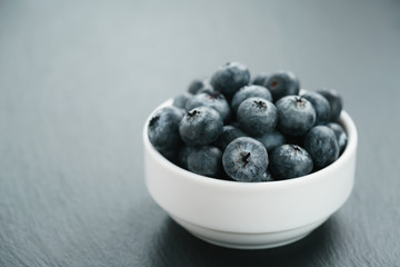 fresh blueberries in white bowl on slate board