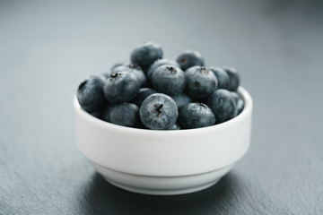 fresh blueberries in white bowl on slate board