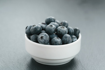 fresh blueberries in white bowl on slate board