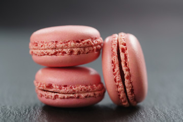 three strawberry macarons on slate board