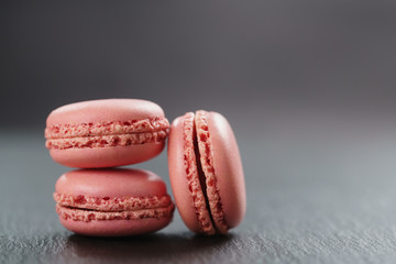 three strawberry macarons on slate board