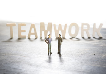 Fototapeta premium TEAMWORK word made from colored wooden letters on wood with miniature business people