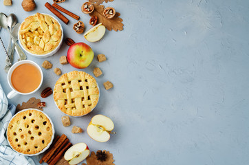 Grey stone background with apple pies, tea and nuts