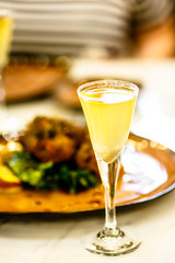 Limoncello in glass on the background of the dish with the meat.