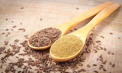 Ground cumin in a spoon and whole cumin