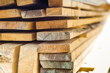 Stack of building lumber at construction site with narrow depth of field. Timber wooden bars.