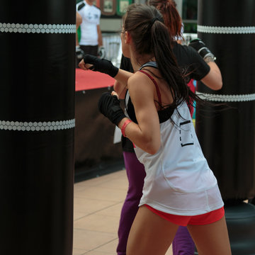 Young Girl with Shorts and White Tank Top: Fitness Boxing Workout with Punching Bag