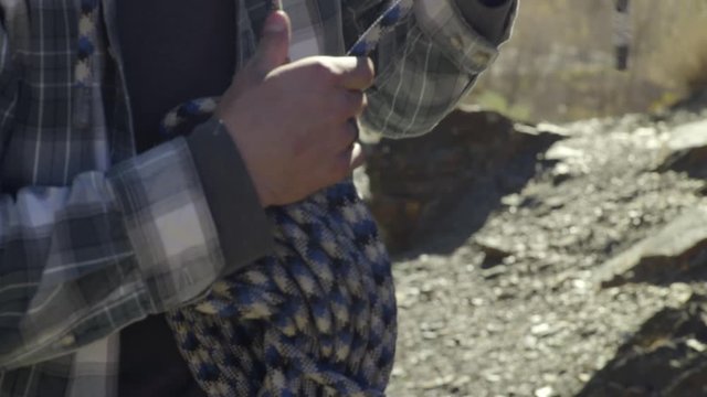 Closeup Of Rock Climber Tying A Knot Around His Climbing Rope, Preparing To Go Home