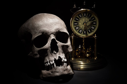 Human skull with vintage clock close up on black background